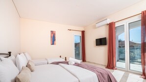 A bedroom with a bed, a flat-screen TV, and a sliding glass door to the outside. - Villa Ocean Pool in Planos (Zakynthos)