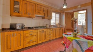 A kitchen with wooden cabinets, a granite countertop, and a dining table with a colorful tablecloth. - Your Island Villas Radazul (El Rosario)