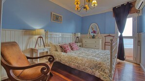 A bedroom with a wooden bed, a chair, a dresser, and a mirror. - Your Island Villas Radazul (El Rosario)