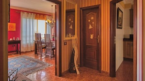 A hallway with striped wallpaper, a wooden door with a Christmas tree design, and a dining area with chairs and a table. - Your Island Villas Radazul (El Rosario)