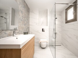 Ein modernes Badezimmer mit Marmor-Waschtisch, einer Duschkabine aus Glas und einer Toilette.