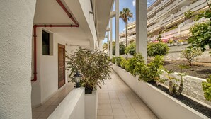 Un pasillo con paredes blancas, una tubería roja, una puerta y una planta en maceta.