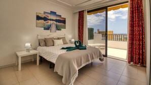 Un dormitorio con una cama, una mesita de noche, un cuadro y vistas al exterior.
