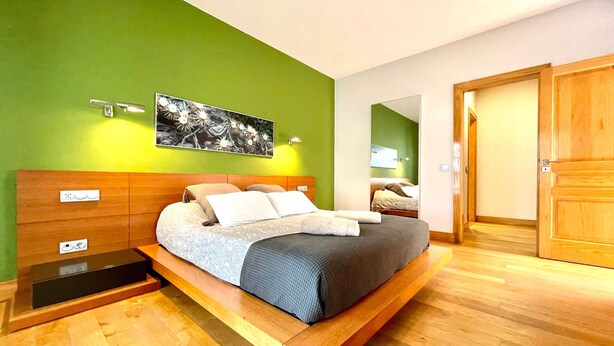 A modern bedroom with a wooden bed, green walls, and a wooden floor. - Your Island Villas Mamma Mia 2 (Yaiza)