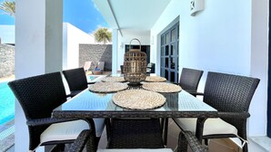 A dining area with a glass table, wicker chairs, and a decorative lantern. - Your Island Villas Mamma Mia 2 (Yaiza)