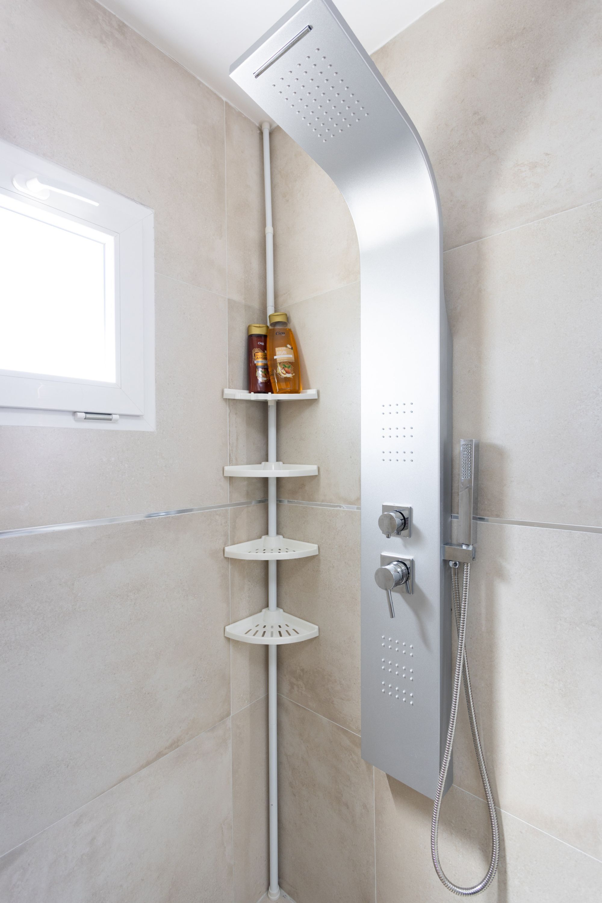 A modern shower with a curved design, a control panel, and a handheld showerhead.