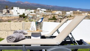 Una silla de descanso con una mesita, un vaso de agua y una toalla.