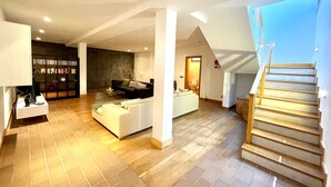 A spacious living area with a modern design, featuring a staircase, a fireplace, and a bookshelf. - Your Island Villa Mamma Mia 1 (Yaiza)