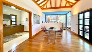 A spacious kitchen with wooden beams, a dining area with a glass table, and large windows offering a view of the outdoors. - Your Island Villa Mamma Mia 1 (Yaiza)