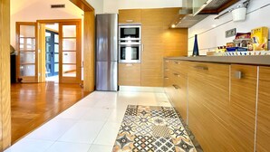 A modern kitchen with wooden cabinets, stainless steel appliances, and a patterned rug. - Your Island Villa Mamma Mia 1 (Yaiza)