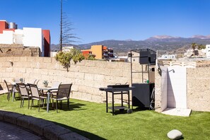 Eine Terrasse im Freien mit Grill, Stühlen und Bergblick.