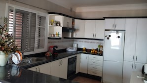 Een moderne keuken met witte kasten, een zwart aanrecht en een roestvrijstalen koelkast.