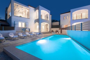 A modern two-story house with a swimming pool, multiple lounge chairs, and a well-lit exterior. - Villa Coral Blue in Planos (Zakynthos)