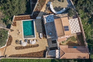 Vista aerea di una proprietà con piscina, zona salotto esterna e tetto in tegole.