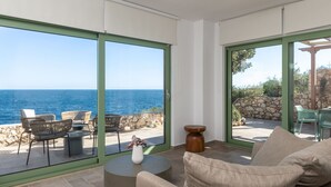 A modern living room with a large sliding glass door leading to an outdoor seating area with a view of the sea. - Evilia Beach Villa in Varvara (Zakynthos)