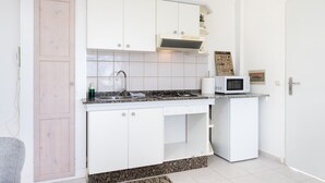 A compact kitchen with white cabinets, a microwave, and a small refrigerator. - Oasis Tenerife Apartamento (Granadilla de Abona)