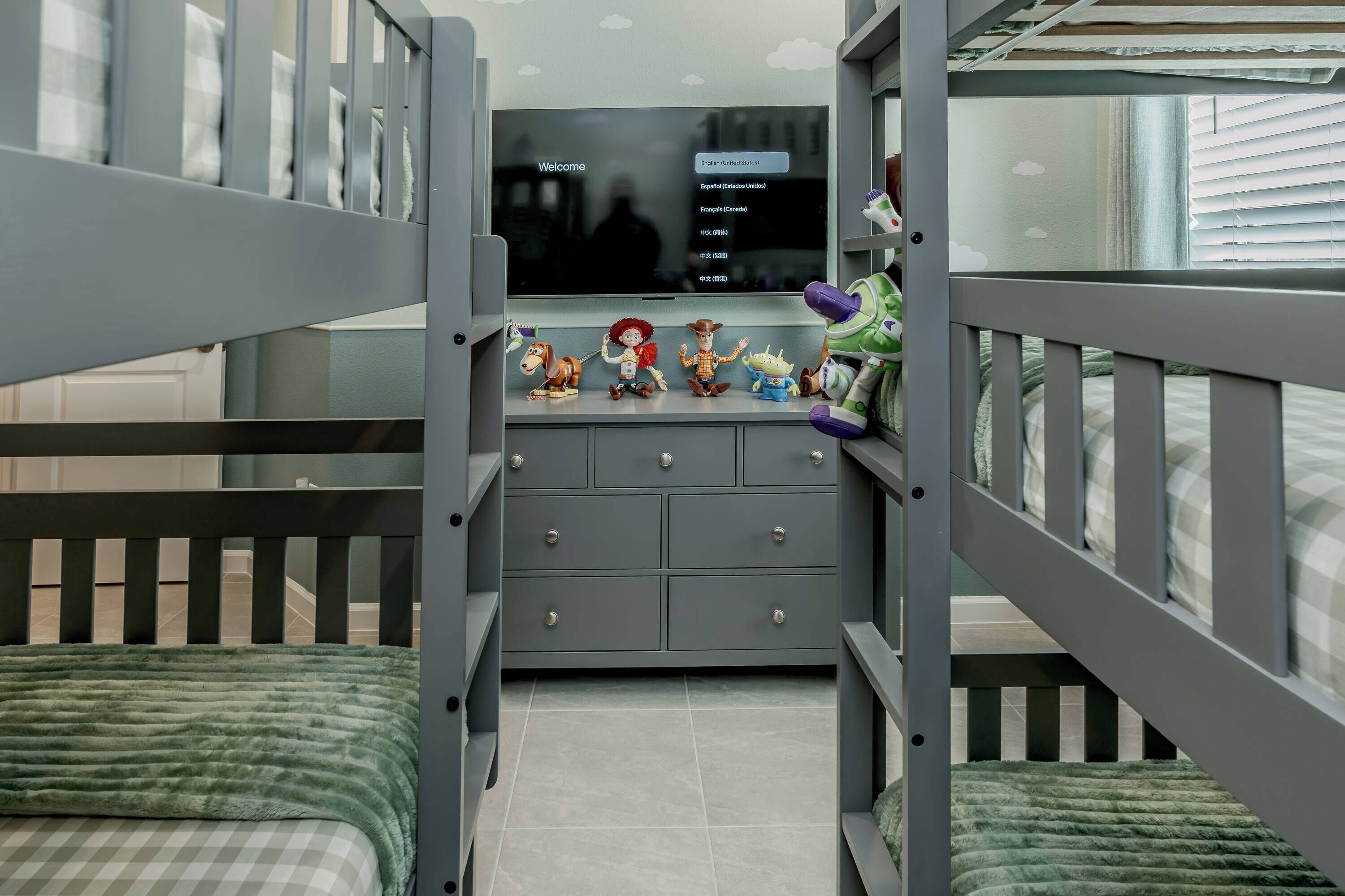 Habitación infantil con literas, televisión y juguetes en un aparador.