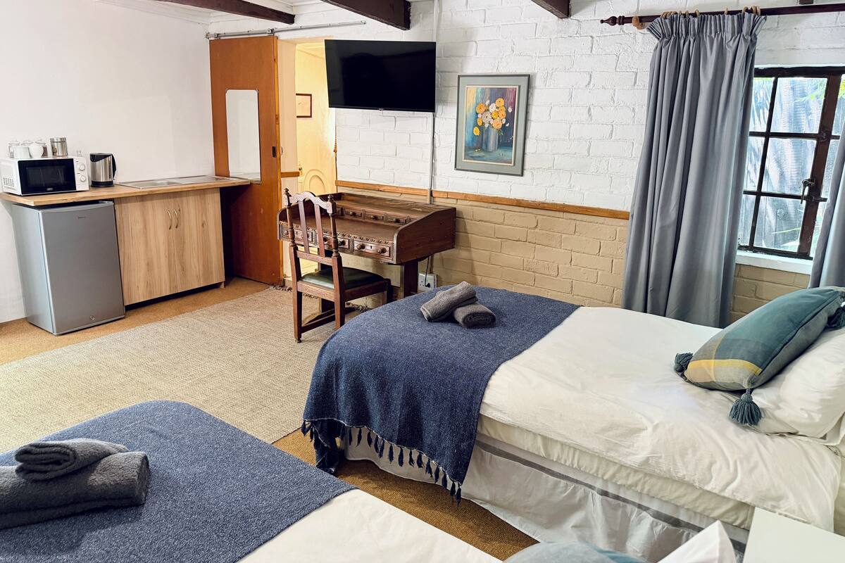 Une chambre avec deux lits, un bureau avec un ordinateur, un four à micro-ondes et un petit réfrigérateur.