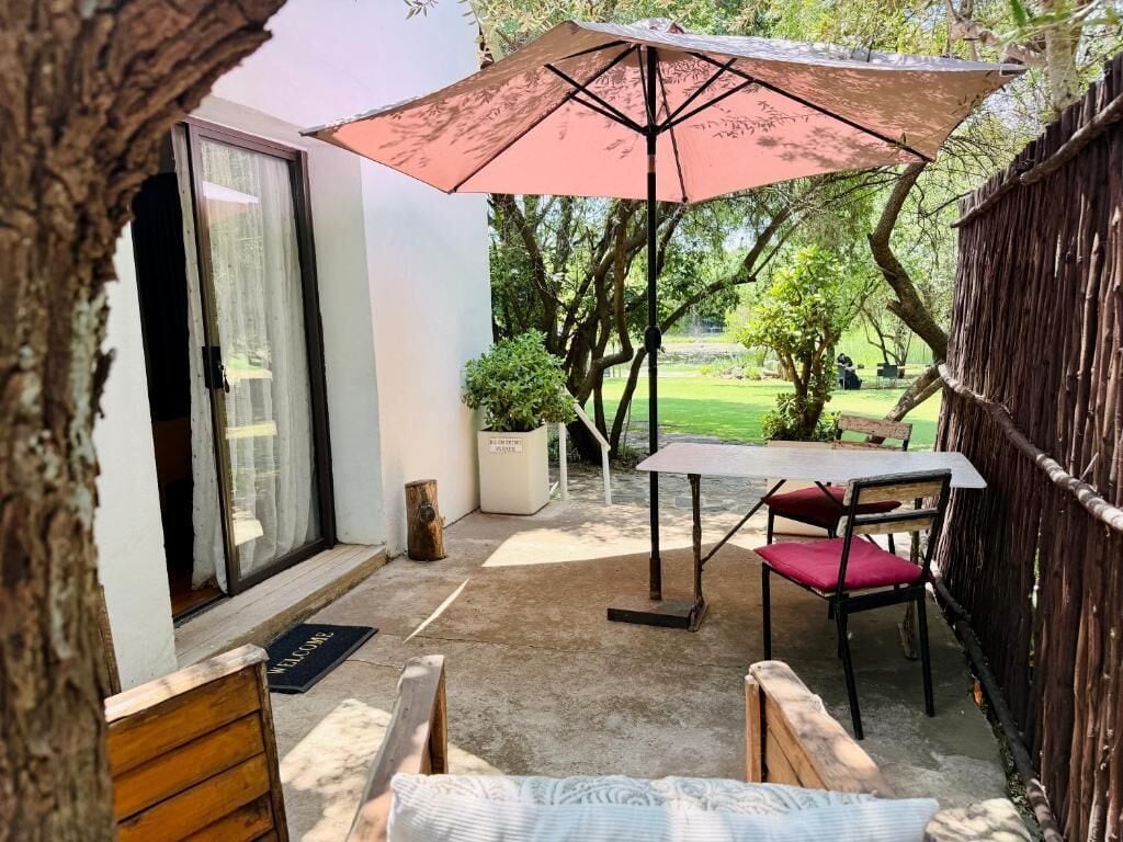 An outdoor patio with a table and chairs, a large umbrella, and a wooden fence.