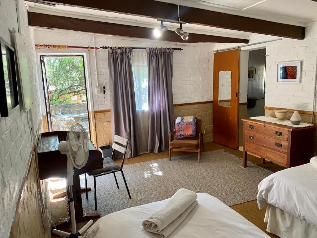 A room with a bed, a wooden dresser, a chair, and a fan.