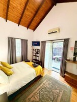 Un dormitorio con cama, televisión, techo de madera y vista al exterior.