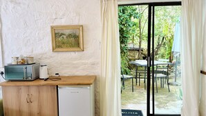 A compact kitchen with a microwave, toaster, and small refrigerator. A wooden counter and a framed picture adorn the wall. - Mizpah Lodge (Bloemfontein)