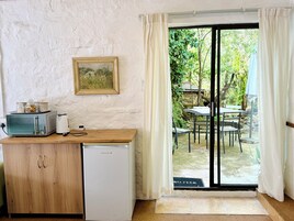 A compact kitchen with a microwave, toaster, and small refrigerator. A wooden counter and a framed picture adorn the wall.