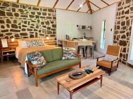 A cozy room with a bed, a sofa, a chair, a coffee table, and a kitchen area.