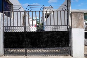 Une entrée fermée par un portail en métal et un mur en béton.