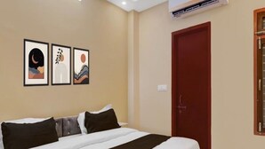 A bedroom with a large bed, a red door, and three framed artworks on the wall. - Hotel O Singar Nagar Metro Station (Lucknow)