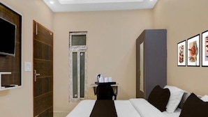 A hotel room with a bed, a desk with a chair, a window, and framed pictures on the wall. - Hotel O Singar Nagar Metro Station (Lucknow)