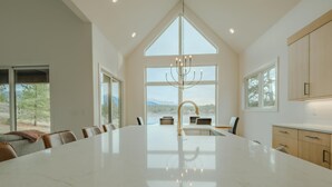 Una cocina amplia con una isla grande, muebles de cocina modernos y ventanas grandes que ofrecen vistas al exterior.