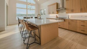 Una cocina moderna con una isla grande, armarios de madera y vistas al exterior.