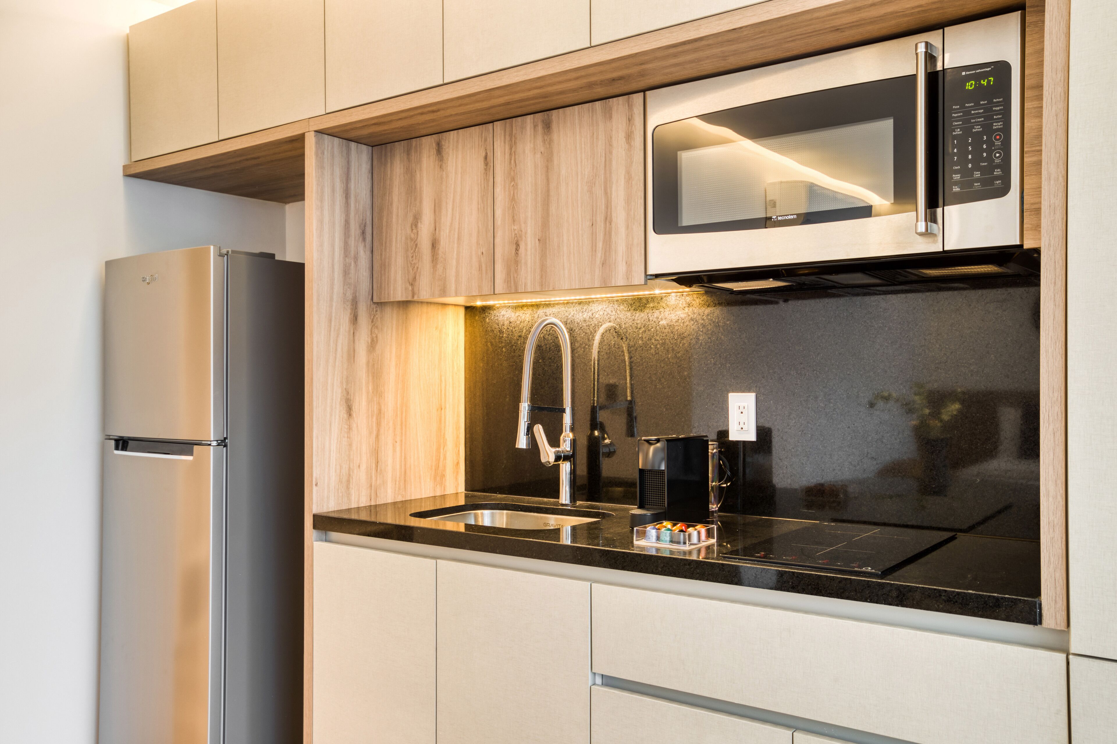 A modern kitchen with a stainless steel refrigerator, a microwave, and a sink with a faucet.
