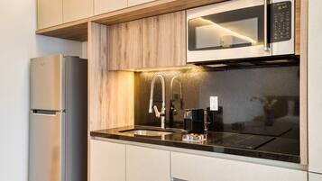 A modern kitchen with a stainless steel refrigerator, a microwave, and a sink with a faucet.