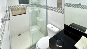 Ein modernes Badezimmer mit einer gläsernen Duschkabine, einer Toilette und einem Waschtisch mit schwarzer Platte.