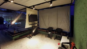 A room with a large screen, two chairs, and a table.