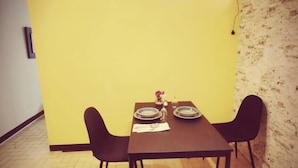 A dining area with a yellow accent wall, two pendant lights, and a table set for two.