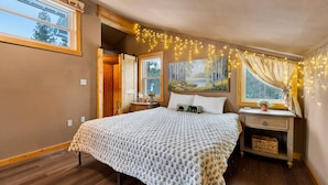 Un dormitorio con cama, mesita de noche, cómoda y un cuadro sobre la cama.