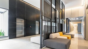 A modern lobby with a seating area, elevators, and a glass wall. - Near the shopping center | Tech hub | Pool #SG05 (Florianópolis)