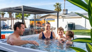 A hot tub with a metal roof and a pool in the background. - Piece of Paradise • Pool, Games, Fire Pit, Hot tub (Glendale)