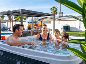 Ein Whirlpool mit Metallüberdachung und einem Pool im Hintergrund.
