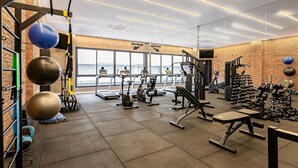 A gym with exercise equipment, a brick wall, and a window. - Near Floripa Shopping | Gym | Technology Hub #SG07 (Florianópolis)