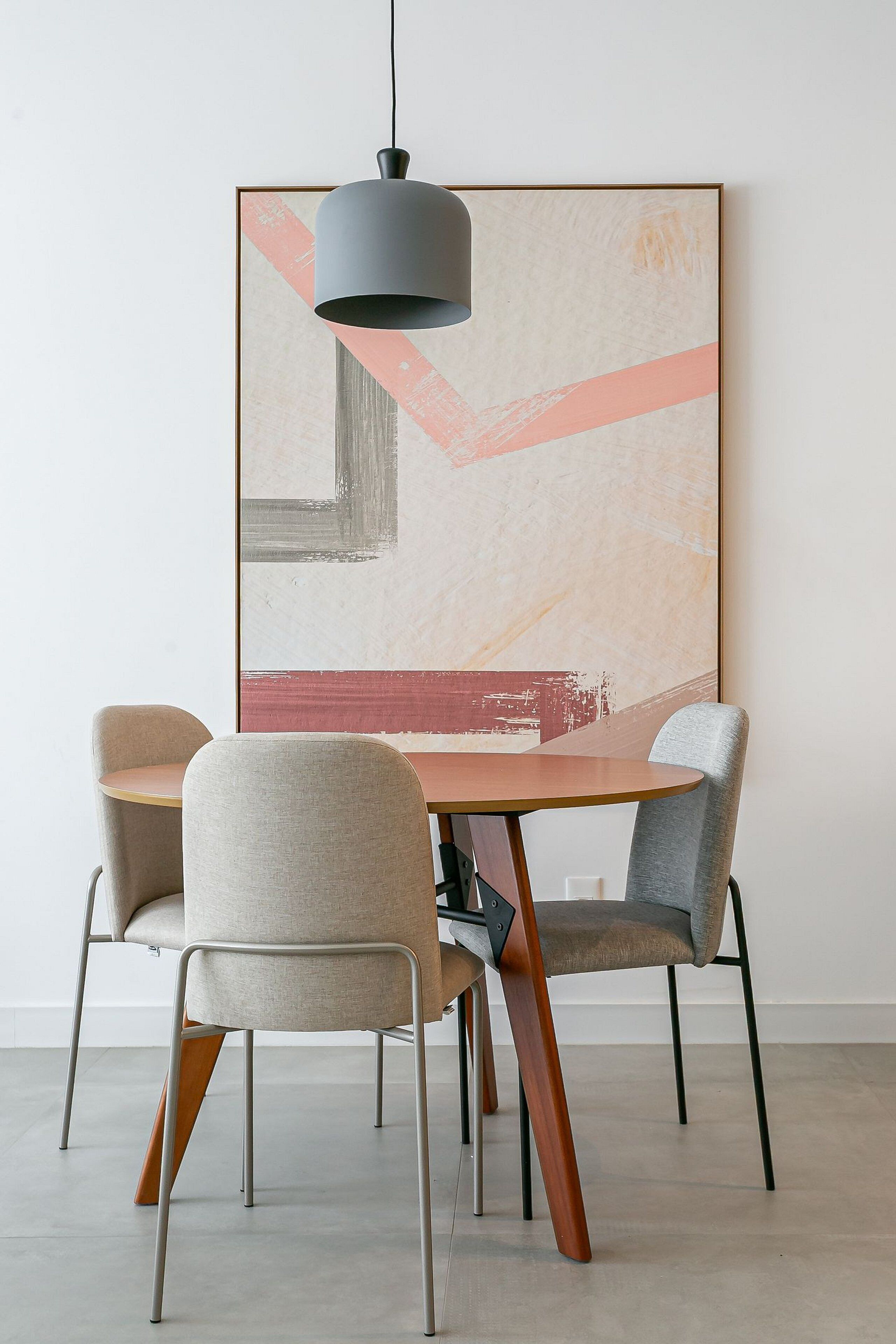 A dining area with a round table, four chairs, and a pendant light.