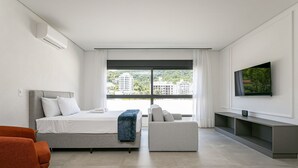 A modern hotel room with a bed, a sofa, a TV, and a city view. - Near Floripa Shopping | Gym | Technology Hub #SG07 (Florianópolis)