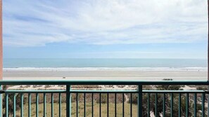 A view from a balcony overlooking a beach with a clear sky.