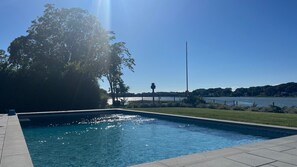 Une piscine avec vue sur un lac et un arbre en arrière-plan.