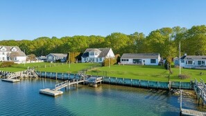 Une propriété située au bord de l’eau, comprenant plusieurs maisons, un quai et une zone herbeuse.