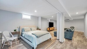 Une chambre moderne comprenant un lit, des tables de chevet, une chaise, un canapé et un téléviseur.