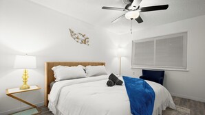 Ein Schlafzimmer mit einem Bett, einem Deckenventilator, einer Wandleuchte, einem Fenster mit Jalousien und einem Wandbild.